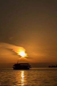 Silhouette boat in sea against orange sky