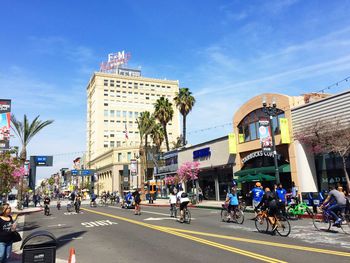 People riding bicycle on street against sky