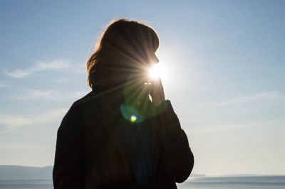 Rear view of woman on beach during sunny day