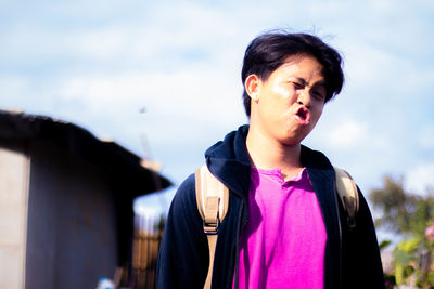 Portrait of young man looking away against sky