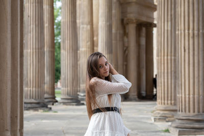 Portrait of smiling young woman standing against built structure