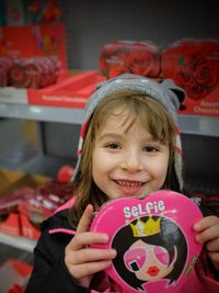 Portrait of smiling cute girl holding heart shape box at store