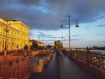 Street amidst buildings against sky during sunset