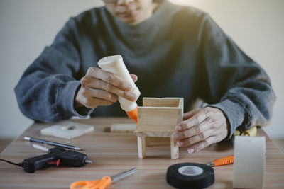 Midsection of man using mobile phone while sitting on table