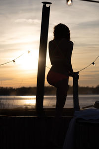 Low angle view of silhouette woman standing at sunset