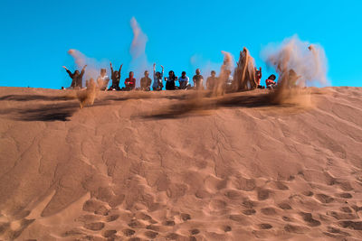 Panoramic view of people on desert against sky