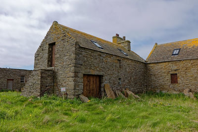 Old house on field against sky