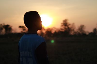 Rear view of silhouette boy against sky during sunset