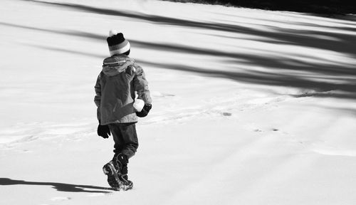 Rear view of girl walking on snow