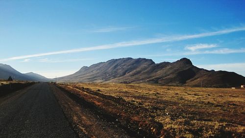 Scenic view of road by mountains against sky