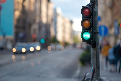 Blurred view of city traffic with traffic lights, in the foreground a semaphore with a green light