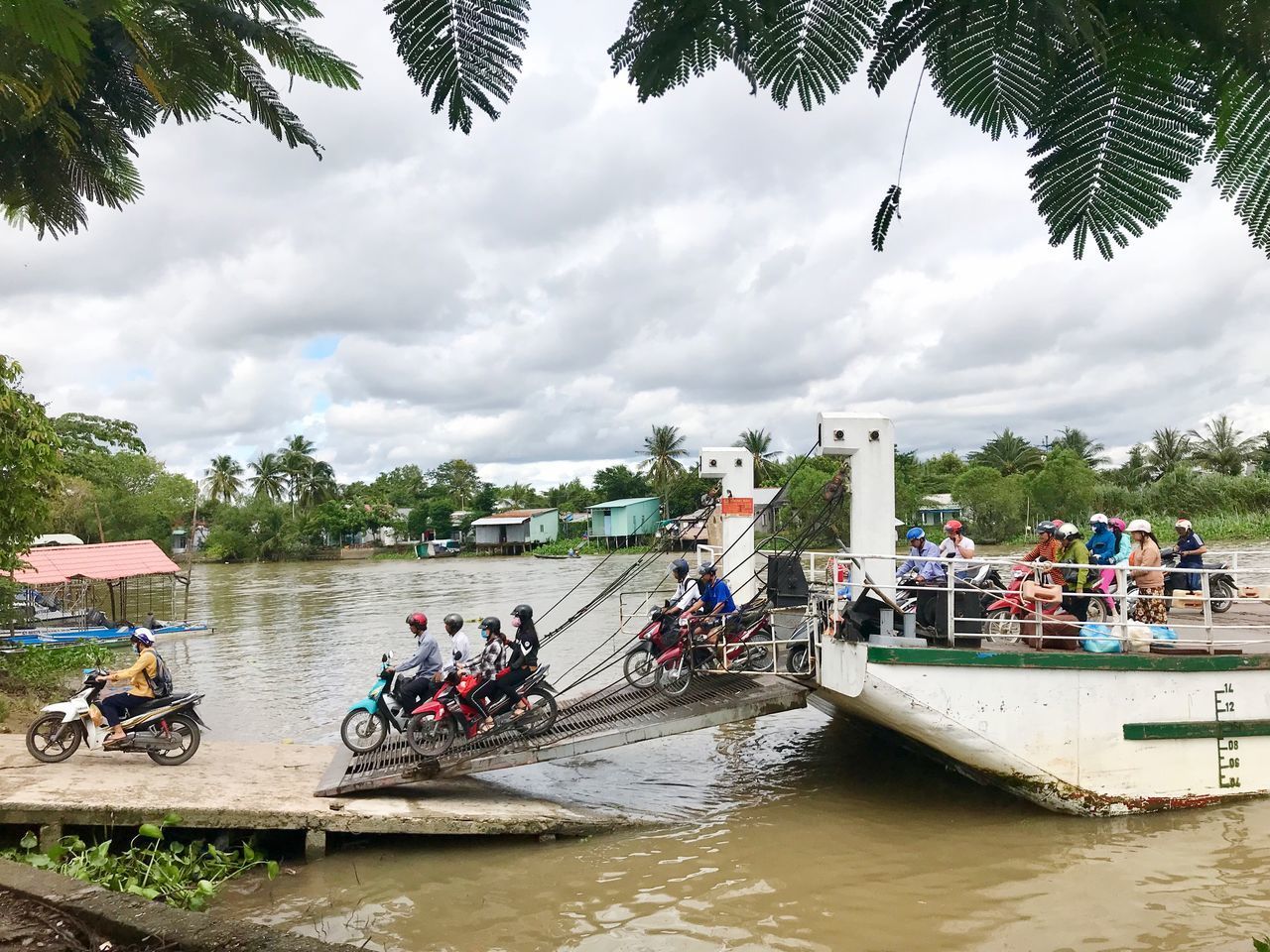 PEOPLE ON RIVERBANK AGAINST SKY