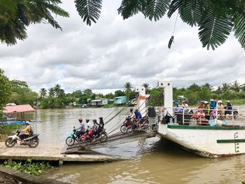 People on boats in river against sky