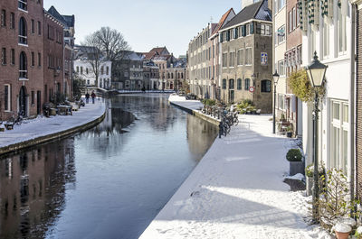 Canal amidst buildings in city against sky