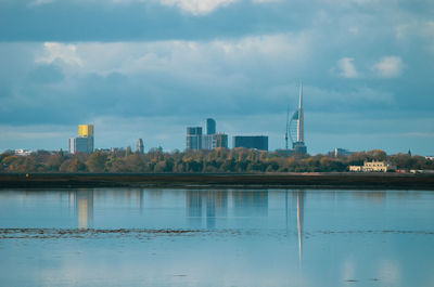 Scenic view of river by buildings against sky