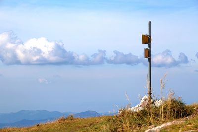 Road sign by landscape against sky