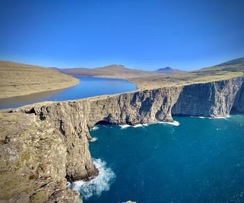 Scenic view of cliff and sea against clear blue sky