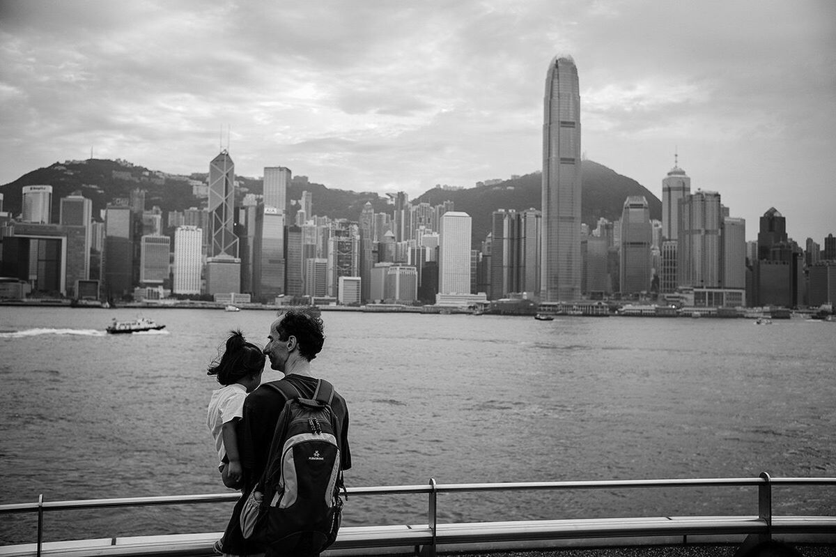 MAN STANDING ON RAILING AGAINST CITYSCAPE