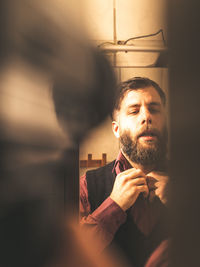 Bearded mid adult man getting dressed at home