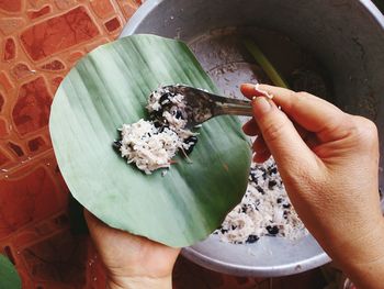 Cropped hand filling banana leaf with rice and bean