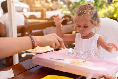 Cropped hand of mother feeding daughter in restaurant