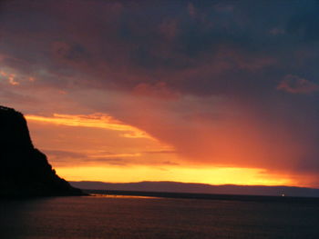 Scenic view of dramatic sky over silhouette mountains during sunset