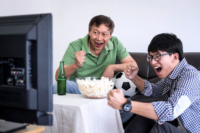 Family with food and drink watching sports on tv at home