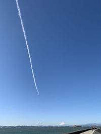 Low angle view of vapor trail against clear blue sky