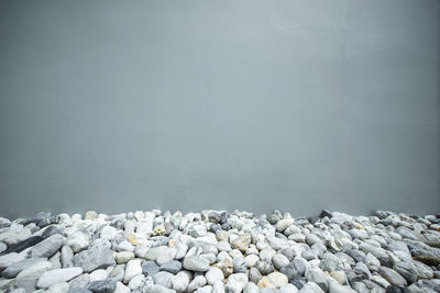 Stones on rocks by lake against clear sky