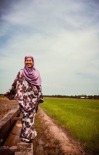 Portrait of smiling woman wearing hijab standing on land against sky