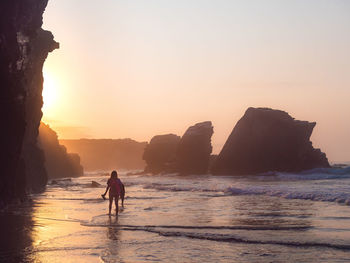 Silhouette people on beach against sky during sunset