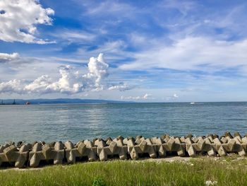 Groynes at sea shore against cloudy sky