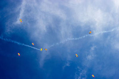 Low angle view of people paragliding against sky