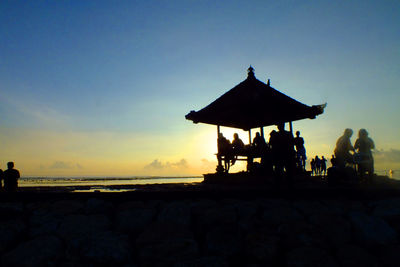 Silhouette rocks on beach against sky during sunset