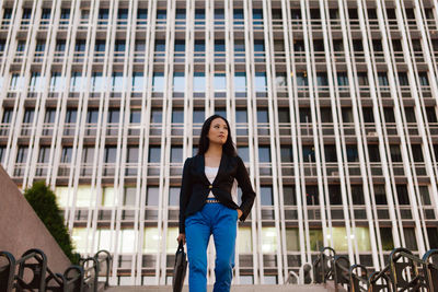 Portrait of woman standing against building in city