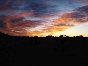 Silhouette landscape against dramatic sky during sunset