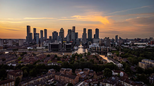 Aerial view of modern buildings in city against sky during sunset