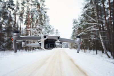 Drone quadcopter with camera flying in the winter forest