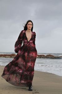 Portrait of woman standing at beach against sky