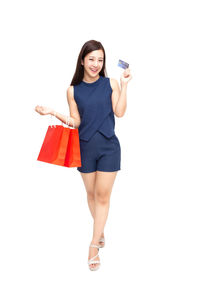 Full length portrait of a smiling young woman standing against white background