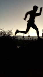 Silhouette man jumping against sky during sunset