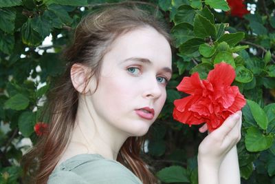 Close-up portrait of woman with red flower