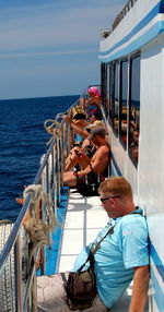 People on boat sailing in sea against sky