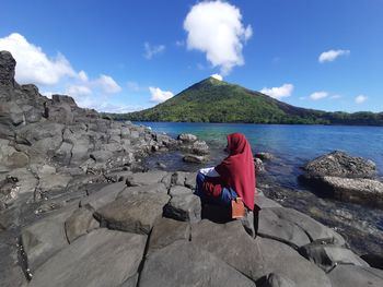 Scenic view of sea by mountain against sky