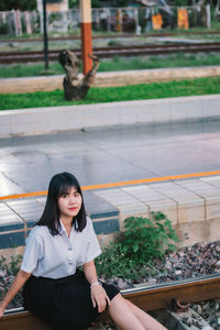 Portrait of woman sitting on railroad track