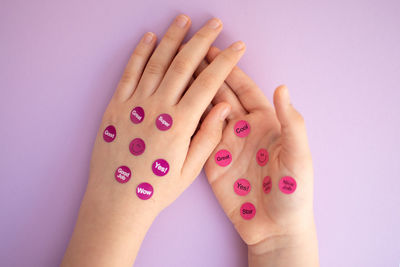 Cropped hands of woman with nail polish against wall