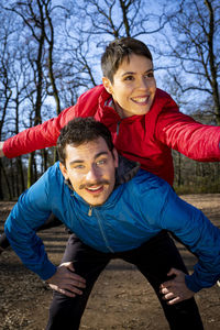 Couple is playing happy in the woods during a workout. man is carrying his girlfriend on his back.