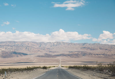 Road by landscape against blue sky