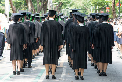 Rear view of students in graduation gown standing at university campus