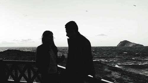 Silhouette people looking at sea against sky